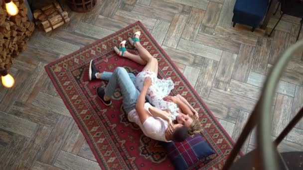Couple heureux de jeunes amants couchés sur le sol sur le tapis et se détendre, vue dessus. — Video