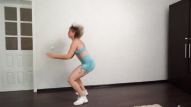 Yan görünüş. Evde dövmeleri olan, çömelmiş ve güzel kalçaları olan bir kız.