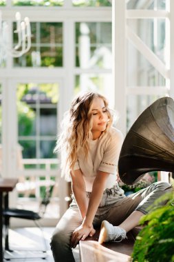 Güneş ışığında antik gramofonun yanında güzel sarışın kız. yüksek tuşlu ışıklandırma