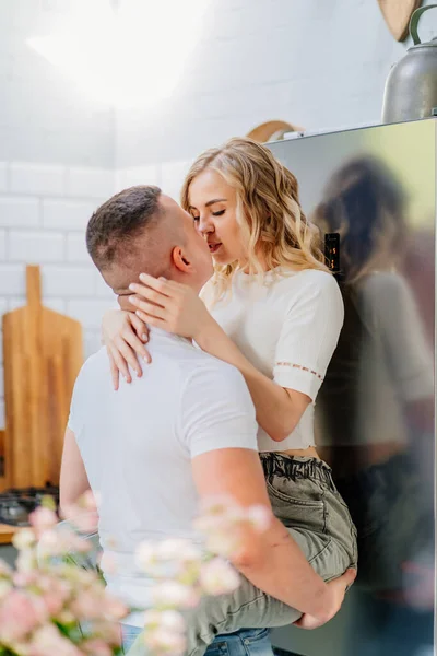 Par de amantes beijando e abraçando na cozinha ao lado da geladeira . — Fotografia de Stock