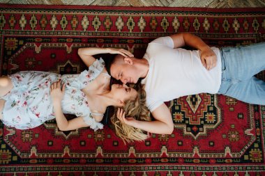 Üstü görünüyor. Mutlu bir çift genç aşık halının üzerinde uzanıyor ve rahatlıyor.