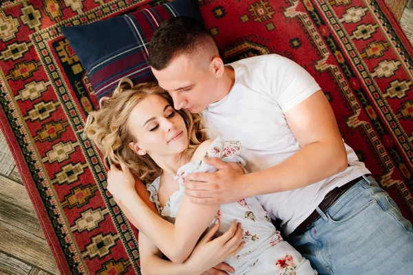 Happy couple of young lovers lying on floor on carpet and relax, view top. — Stock Photo, Image