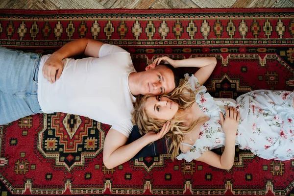 View top. happy couple of young lovers lying on floor on carpet and relax. — Stock Photo, Image