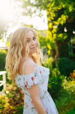 Bahçede yürüyen yazlık elbiseli güzel sarışın kız..