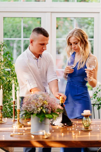 Влюбленная счастливая пара на романтическом ужине со стеклом. Парень наливает шампанское. — стоковое фото