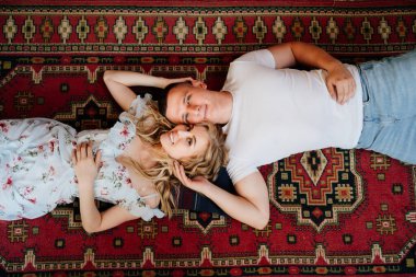 Üstü görünüyor. Mutlu bir çift genç aşık halının üzerinde uzanıyor ve rahatlıyor.