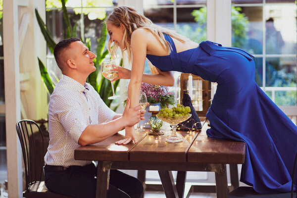 romantic dinner. girl with glass of wine stands on table to kiss boyfriend.