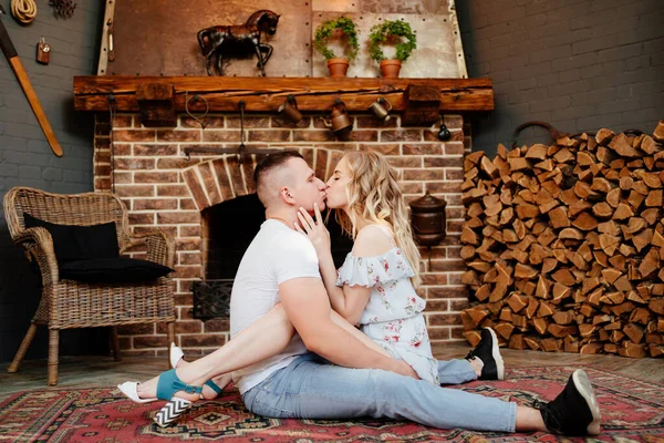 Lovers are sitting on carpet in front of fireplace. — Stock Photo, Image