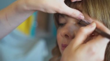 Yakın plan. Makyöz kadına makyaj yapıyor..