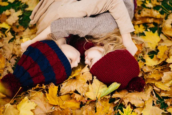 Маленькі дівчата в капелюсі лежать на жовтому осінньому листі . — стокове фото