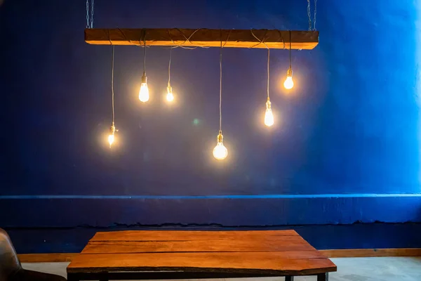 interior. wooden table, lamp hanging. blue wall.