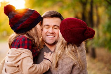Batan güneş. Kızı babasını yanağından öpüyor. Mutlu aile kavramı.