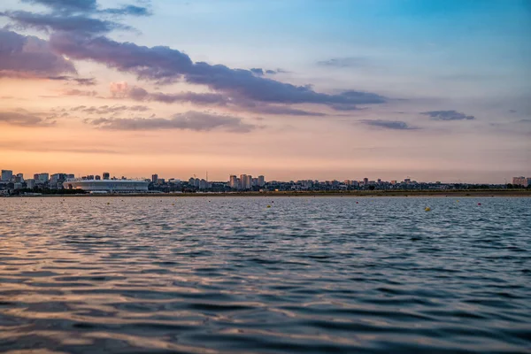 Coucher de soleil en soirée sur l'eau avec vue sur la ville — Photo