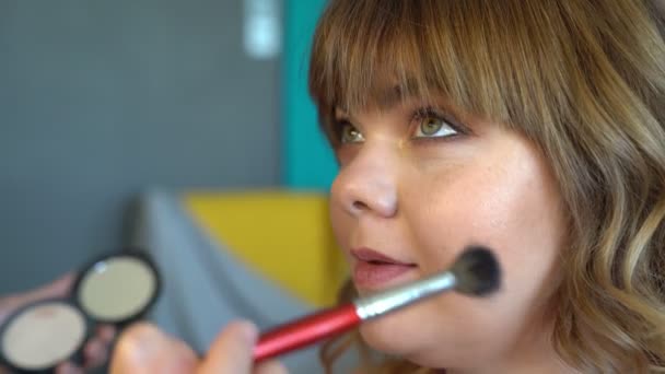 Yakın plan. Makyaj yapan makyöz kadın pudrayı fırçayla sürüyor. — Stok video