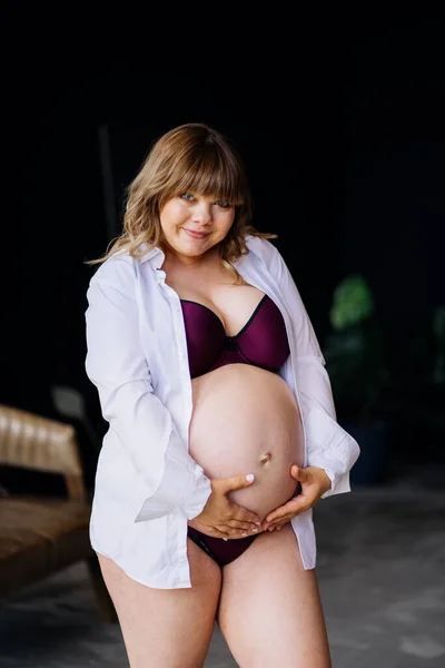 Gravid kvinna med övervikt i underkläder stående och stroking mage. — Stockfoto