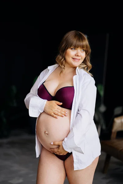 Mulher grávida com excesso de peso em roupa interior em pé e acariciando barriga . — Fotografia de Stock
