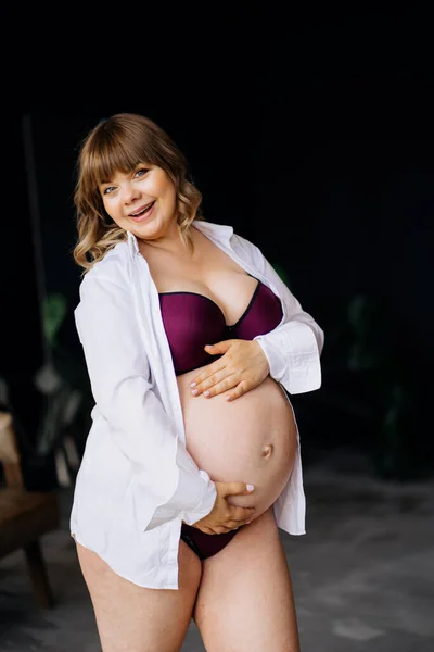 Gravid kvinna med övervikt i underkläder stående och stroking mage. — Stockfoto