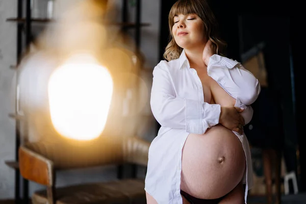 Üstsüz, beyaz tişörtlü, kilolu hamile bir kadın. vücut pozitifi. — Stok fotoğraf