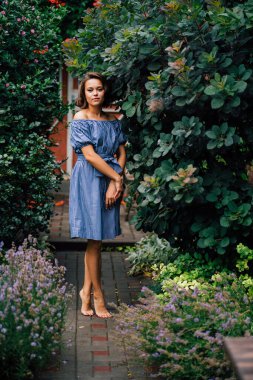 Güzel esmer kız, yazlık bahçede çıplak ayakla yürüyor kır evinin arka bahçesinde.