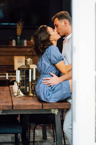 Vista através da porta de rua para casal beijando perto de mesa de madeira . — Fotografia de Stock
