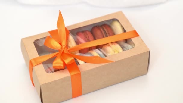 Le mani dei bambini slegano l'arco sulla confezione regalo con macaron multicolore — Video Stock