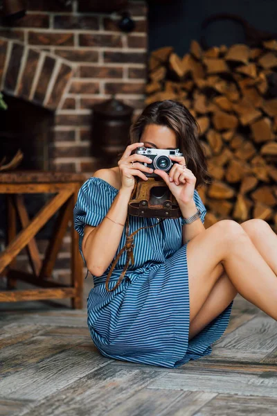 Menina bonita sentado no chão na casa de campo com câmera retro nas mãos . — Fotografia de Stock