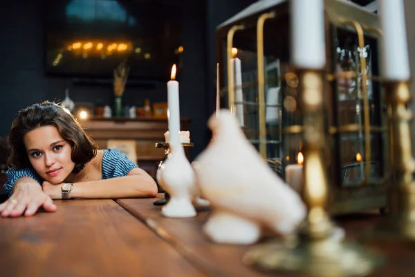 Atractiva morena se tumbó sobre una mesa de madera con vela. — Foto de Stock