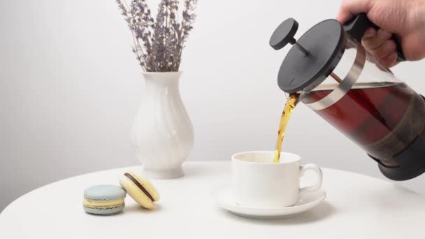 Em copo branco para derramar chá. configuração de mesa com vaso com lavanda e macarons . — Vídeo de Stock