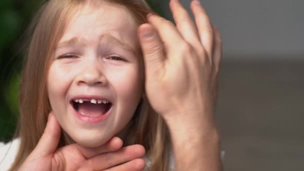 Dad's hand wobbles baby tooth of little daughter. — Stock Video