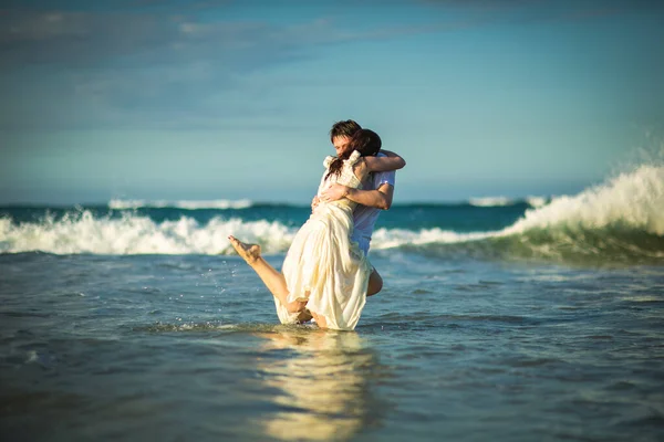 Casal em roupas brancas na água na praia . — Fotografia de Stock