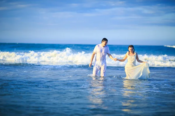 Paar in nassen Klamotten geht am Strand ins Wasser. — Stockfoto