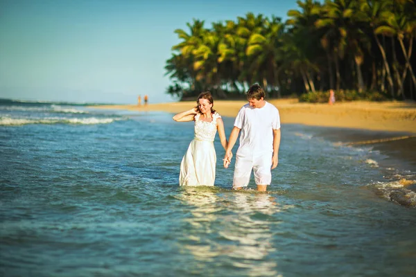 Casal em roupas brancas na água na praia . — Fotografia de Stock