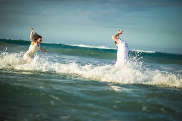 Пара в белой одежде, бегущая в воде на пляже. — стоковое фото