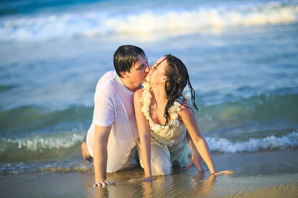 Nouvellement mariés en vêtements humides flirter couché sur la plage. — Photo