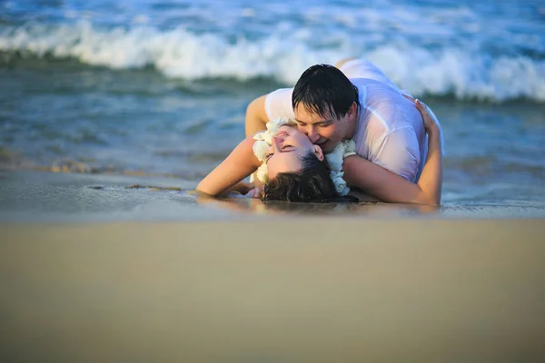 Nygifta i våta kläder flörtande liggande på stranden. — Stockfoto