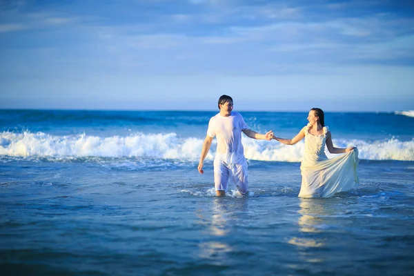 Par i våta kläder går i vatten på stranden. — Stockfoto