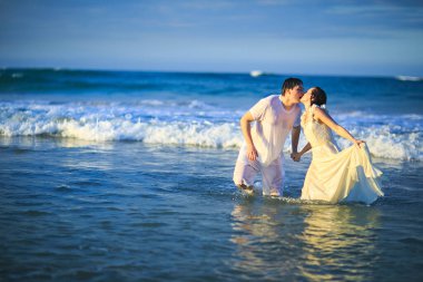 Islak elbiseli çift kumsalda suya giriyor..