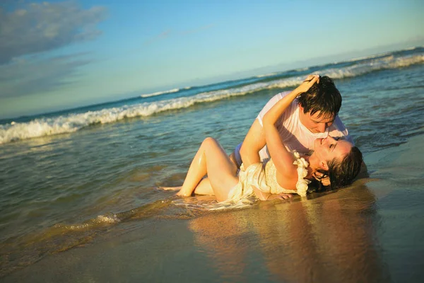 Мокрые любовники лежат на пляже в воде и целуются. — стоковое фото