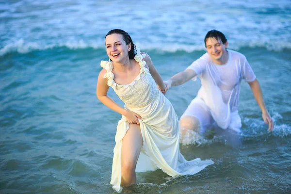 Mulher leva homem à mão na água do mar na praia . — Fotografia de Stock