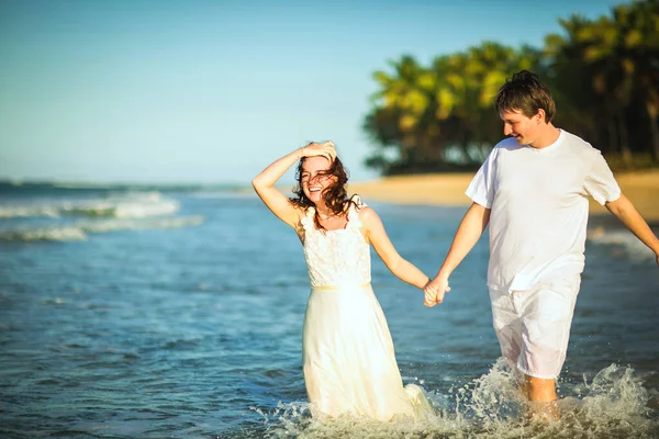 Casal em roupas brancas na água na praia . — Fotografia de Stock