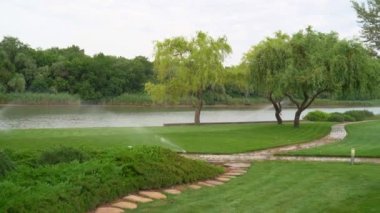 Nehir kenarındaki çimlerin sulama sistemi. Yazın park et..