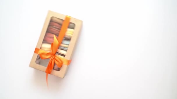 Paquete con cinta y macarons interior entra en el fondo blanco. — Vídeo de stock