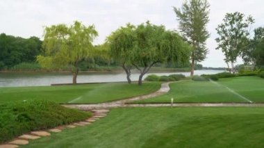 Nehir kenarındaki çimlerin otomatik sulama sistemi. Yazın park et..