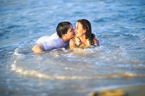 Pasgetrouwd in natte kleren flirten liggend op het strand. — Stockfoto