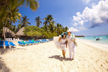 Turistler kumlu kumsalda yürüyorlar..