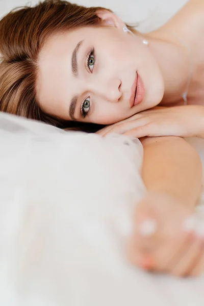 Menina com maquiagem natural, pele brilhante encontra-se na cama — Fotografia de Stock