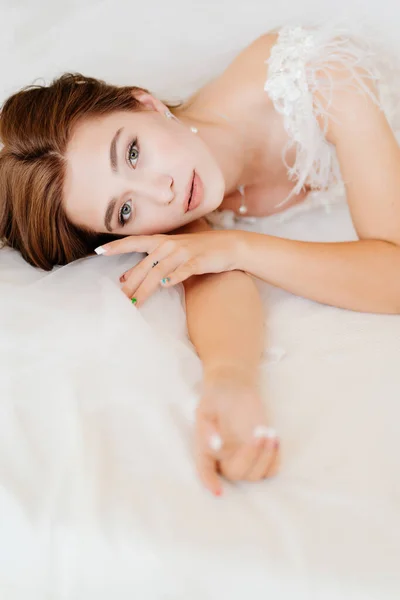 Novia con maquillaje natural en vestido acostado en la cama. — Foto de Stock
