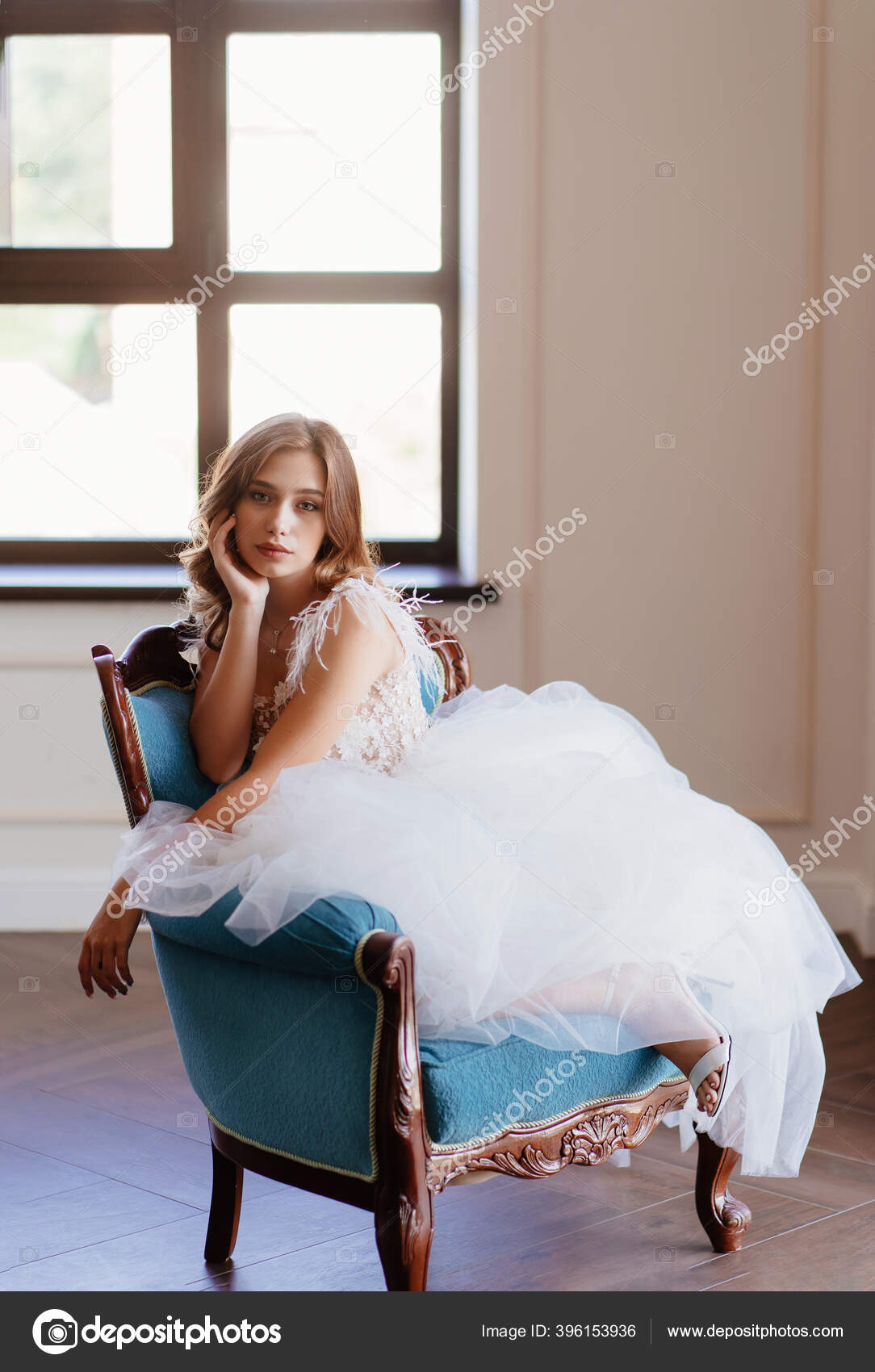 Beautiful bride in white dress sit in blue chair Stock Photo by