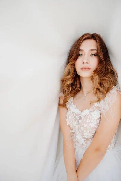 Hermosa novia en vestido blanco sobre fondo de tela blanca — Foto de Stock