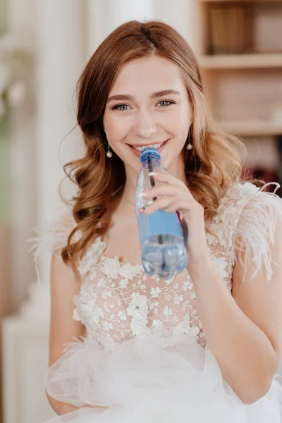 Bruden dricker vatten från flaskan genom sugrör för att inte förstöra makeup. — Stockfoto